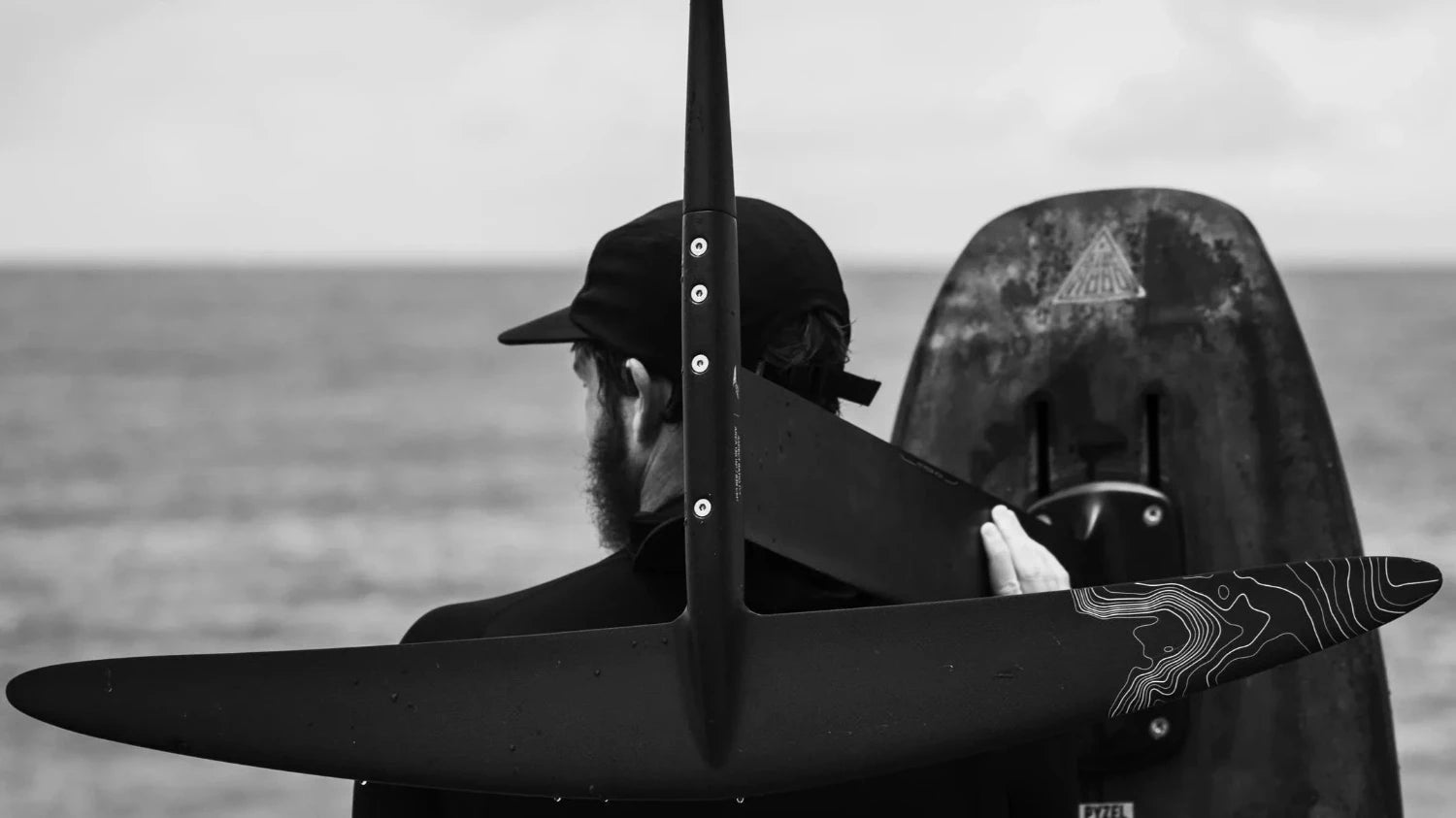 Lifestyle picture of a foiler holding a Lift hydrofoil mounted on a foilboard